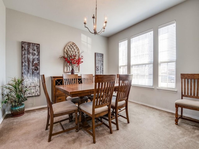 dining room with light carpet, an inviting chandelier, and baseboards