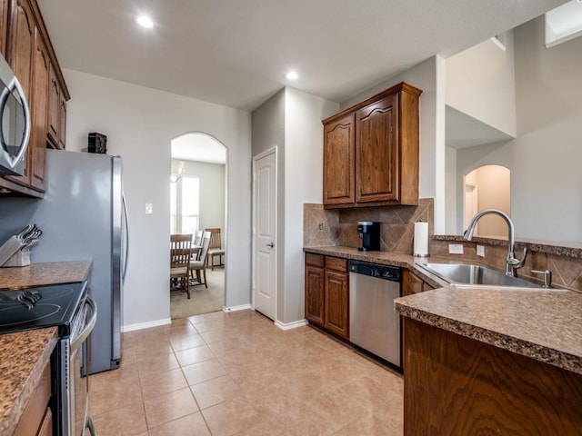 kitchen with recessed lighting, arched walkways, a sink, stainless steel appliances, and tasteful backsplash