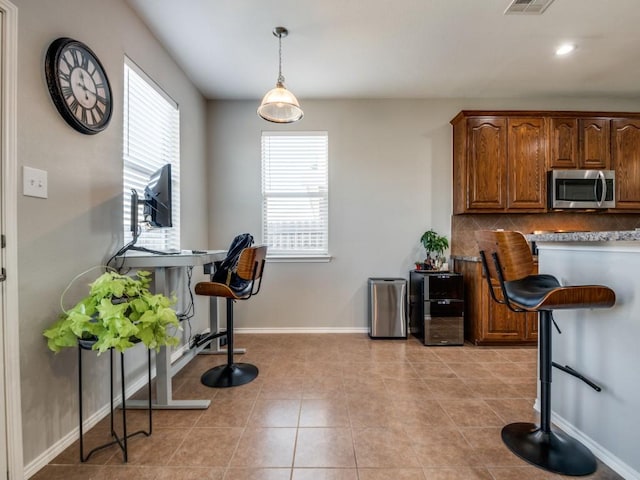 kitchen featuring a wealth of natural light, stainless steel microwave, baseboards, and decorative backsplash