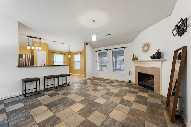 living area with visible vents, baseboards, lofted ceiling, and a fireplace