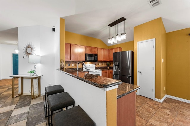 kitchen featuring a kitchen bar, visible vents, black appliances, a peninsula, and decorative backsplash