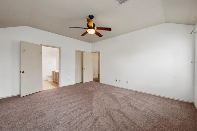 unfurnished bedroom with ensuite bath, lofted ceiling, visible vents, and light carpet