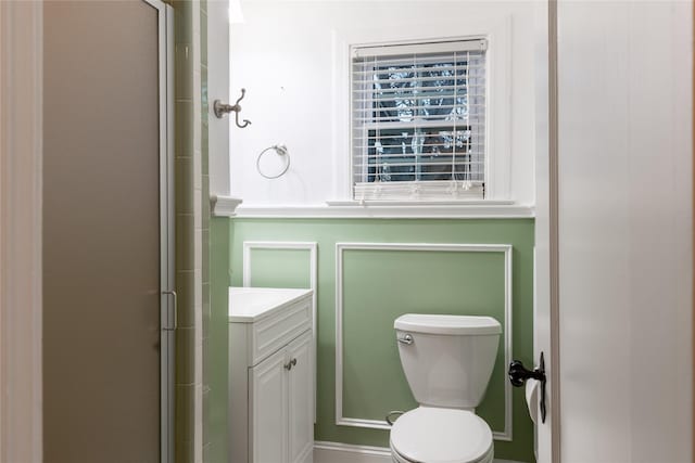 bathroom featuring toilet, a shower with door, and vanity