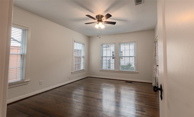 empty room featuring visible vents, dark wood finished floors, and baseboards