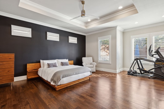 bedroom with a tray ceiling, baseboards, and wood finished floors