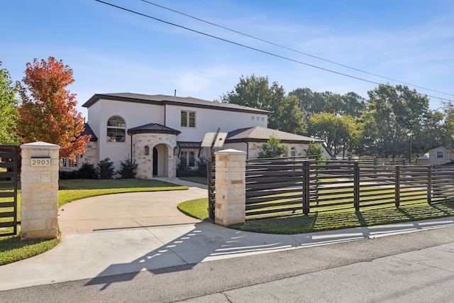 view of front facade featuring a fenced front yard, a front yard, a standing seam roof, metal roof, and driveway