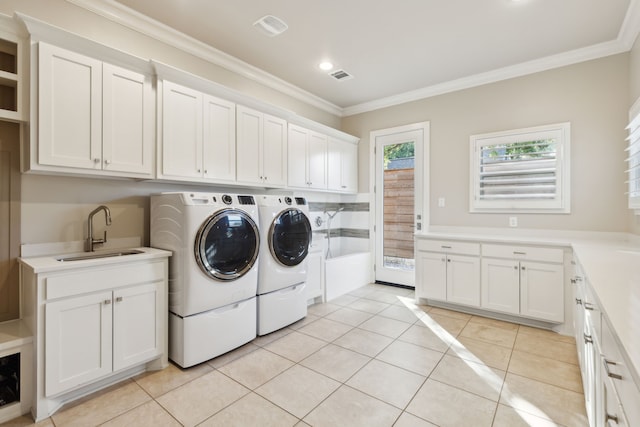 laundry area featuring light tile patterned floors, washing machine and dryer, a sink, ornamental molding, and cabinet space