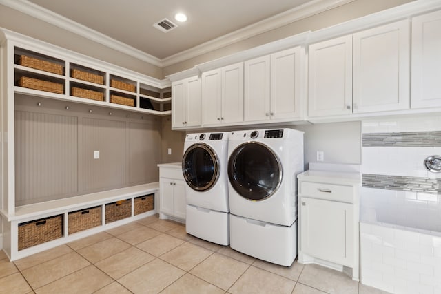 clothes washing area featuring light tile patterned flooring, separate washer and dryer, visible vents, ornamental molding, and cabinet space