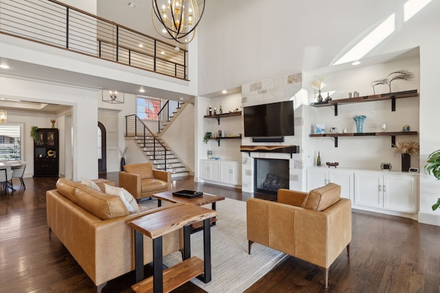 living area featuring a large fireplace, dark wood finished floors, and an inviting chandelier