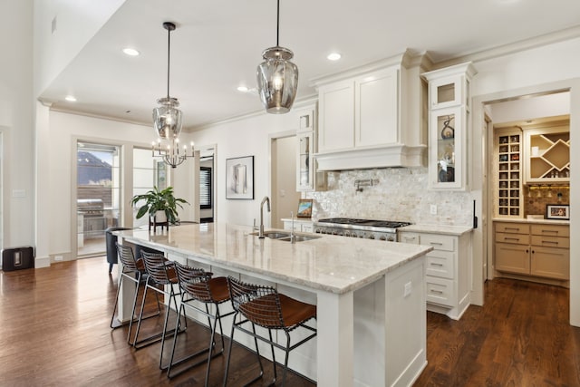 kitchen with a breakfast bar area, dark wood-style flooring, stove, a sink, and backsplash