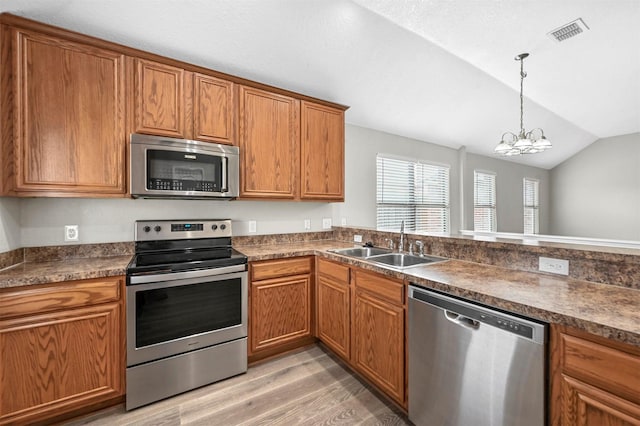 kitchen featuring stainless steel appliances, lofted ceiling, visible vents, brown cabinetry, and a sink