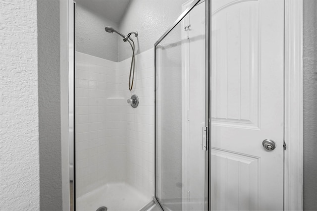 full bathroom with a textured wall and a stall shower