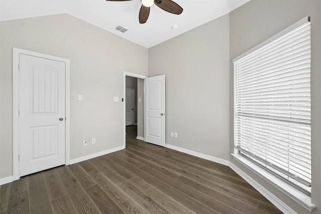 unfurnished bedroom featuring dark wood-style floors, visible vents, vaulted ceiling, and baseboards