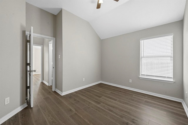 spare room with dark wood-type flooring, vaulted ceiling, baseboards, and a ceiling fan