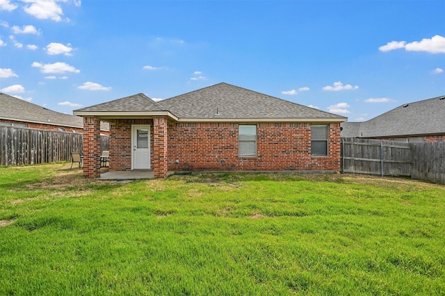 rear view of property with brick siding, a lawn, and a fenced backyard