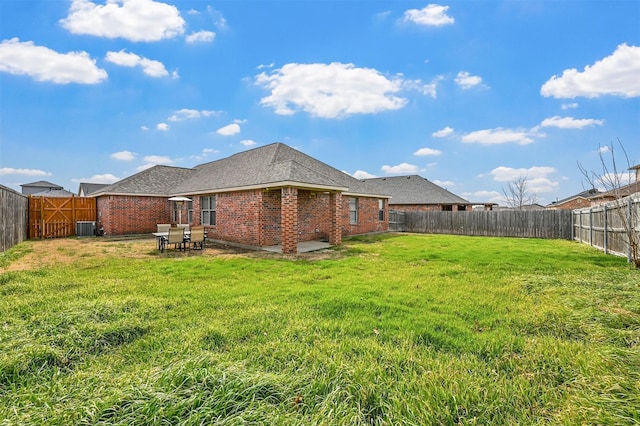 back of house with central AC, brick siding, a lawn, and a fenced backyard