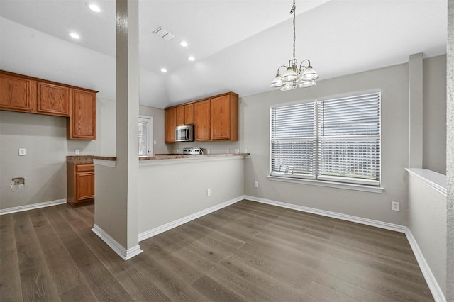 kitchen featuring brown cabinetry, dark wood-style flooring, stainless steel microwave, and visible vents