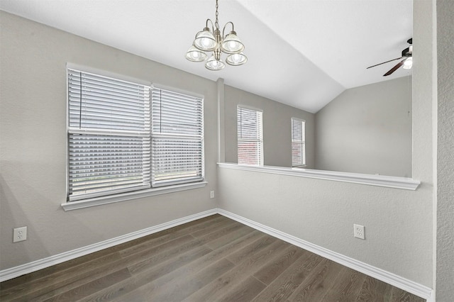 empty room with vaulted ceiling, ceiling fan with notable chandelier, dark wood finished floors, and baseboards