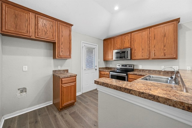 kitchen with stainless steel appliances, dark wood finished floors, brown cabinets, and a sink