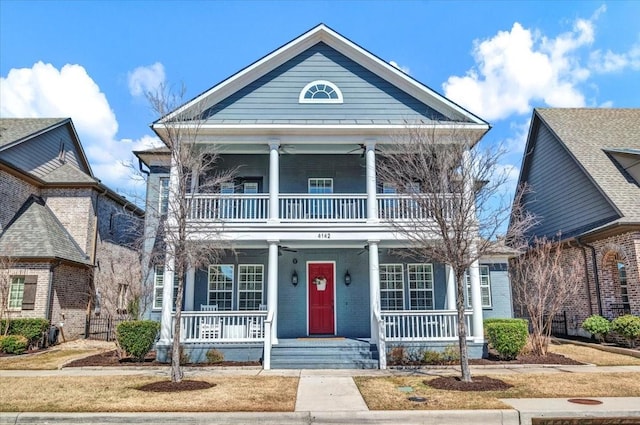 greek revival inspired property with a ceiling fan, covered porch, brick siding, and a balcony