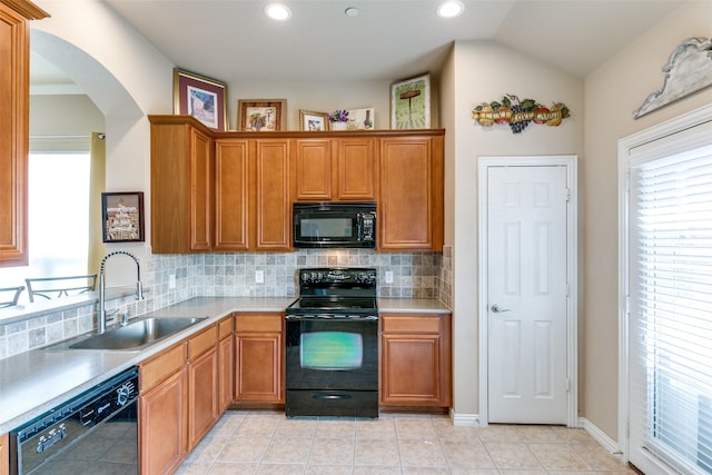 kitchen featuring a healthy amount of sunlight, black appliances, backsplash, and a sink