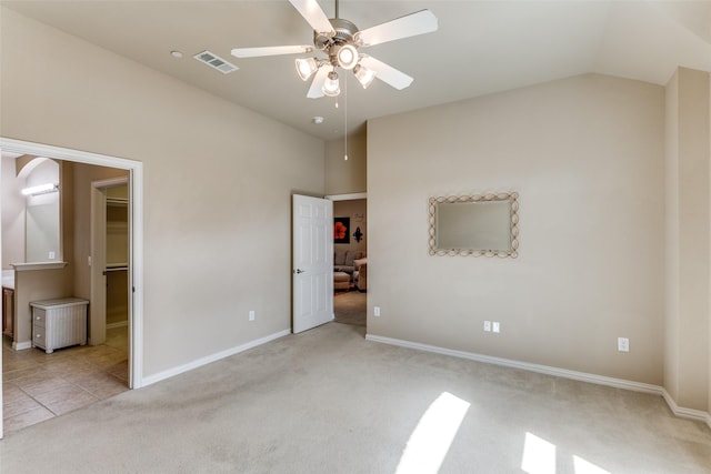 unfurnished bedroom featuring light colored carpet, vaulted ceiling, visible vents, and baseboards