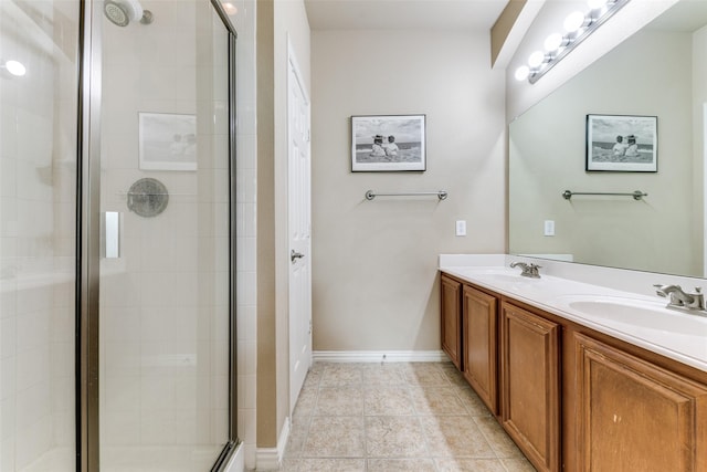 full bath with a stall shower, a sink, baseboards, and double vanity