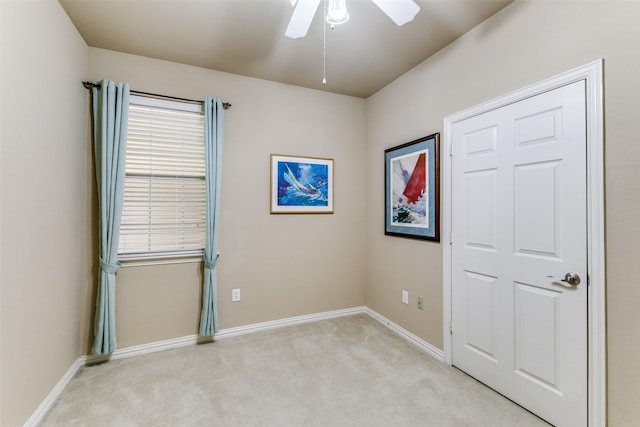 spare room with baseboards, ceiling fan, and light colored carpet