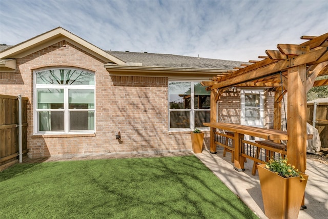 back of property with brick siding, fence, a pergola, and a yard