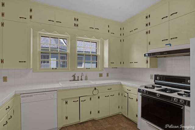 kitchen with tile countertops, under cabinet range hood, white appliances, a sink, and tasteful backsplash