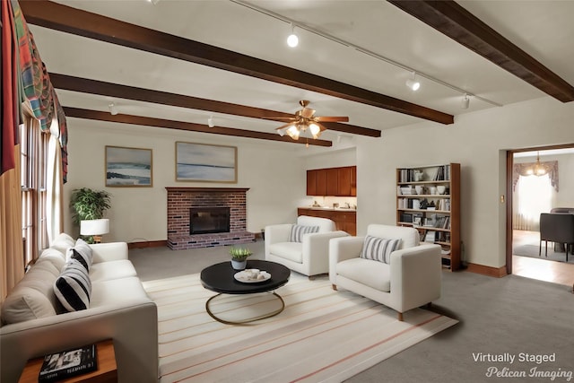 living room with beam ceiling, a fireplace, light colored carpet, track lighting, and baseboards