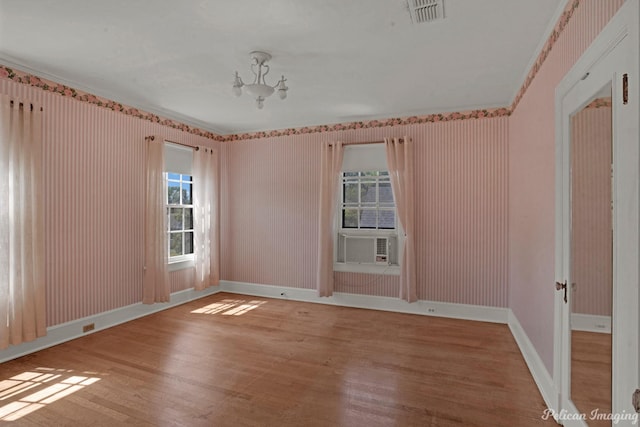 unfurnished room with a wealth of natural light, visible vents, baseboards, and wood finished floors