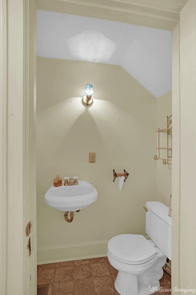 bathroom with vaulted ceiling, a sink, toilet, and baseboards