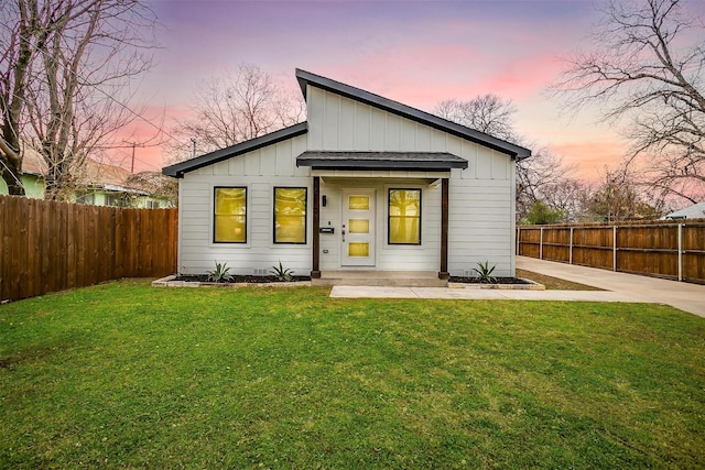 back of house featuring board and batten siding, a fenced backyard, and a yard