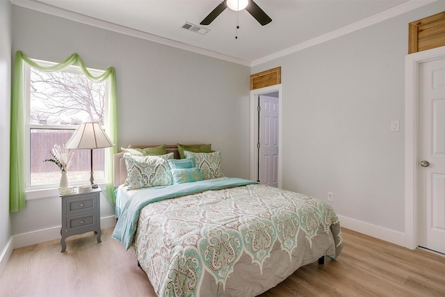 bedroom featuring baseboards, wood finished floors, visible vents, and crown molding