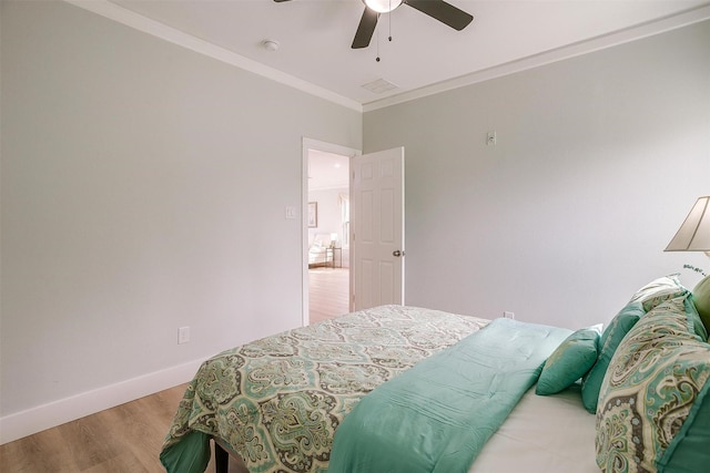 bedroom with ceiling fan, wood finished floors, visible vents, baseboards, and crown molding