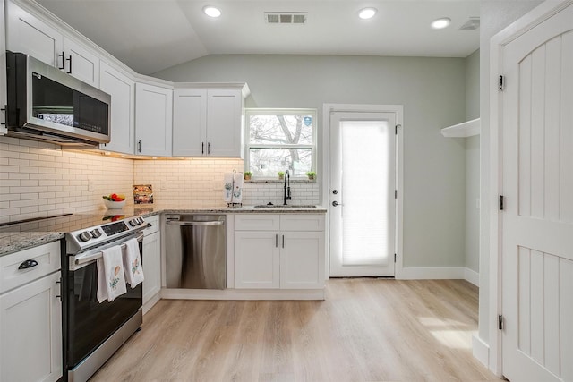 kitchen featuring stainless steel appliances, a healthy amount of sunlight, a sink, and light stone countertops