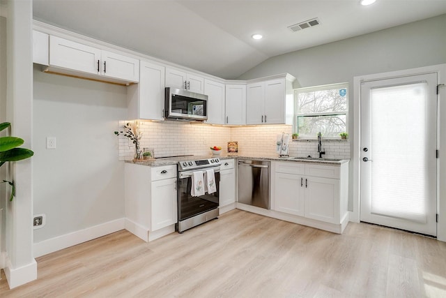 kitchen with visible vents, appliances with stainless steel finishes, a sink, and light stone counters