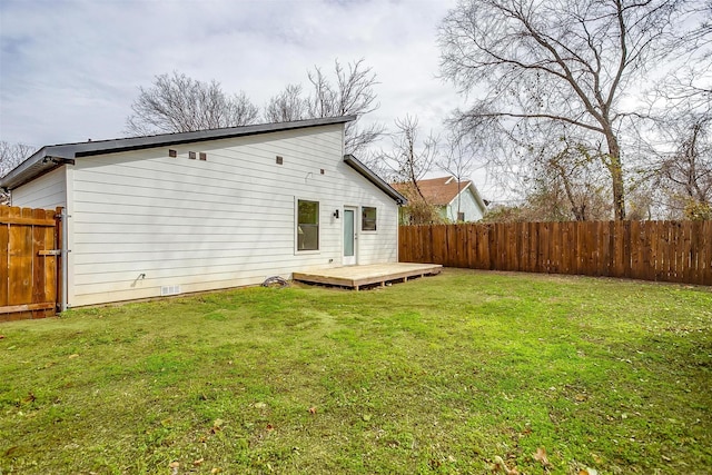 rear view of house featuring fence, a lawn, and a wooden deck