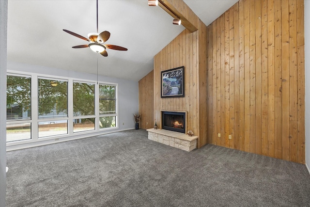 unfurnished living room featuring carpet floors, wood walls, beam ceiling, and a stone fireplace