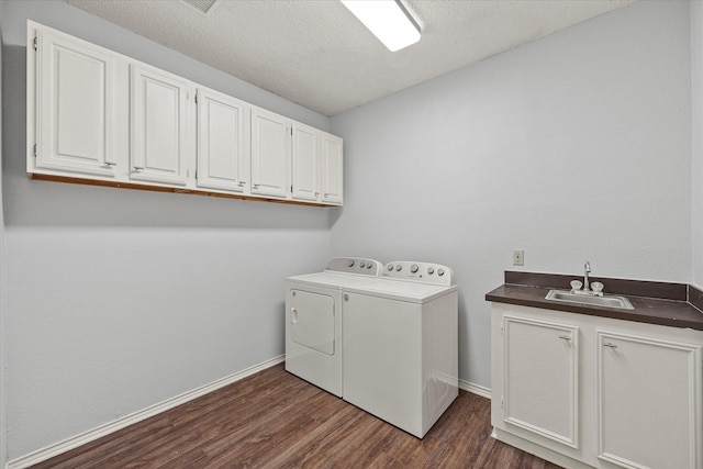 laundry area with cabinet space, dark wood-type flooring, a sink, a textured ceiling, and separate washer and dryer