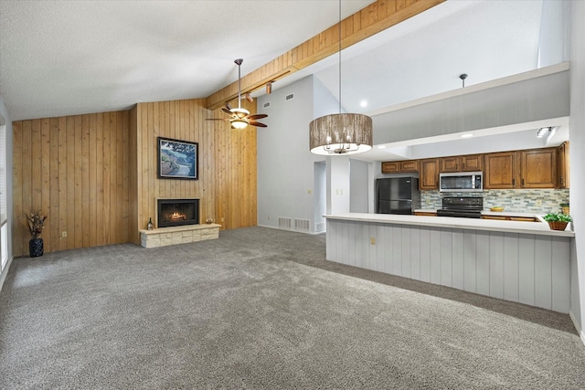 unfurnished living room with carpet, a lit fireplace, a textured ceiling, wood walls, and beam ceiling