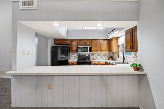 kitchen with light countertops, visible vents, backsplash, a sink, and black appliances