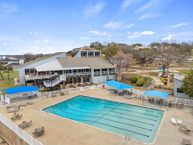 community pool with a patio area and fence