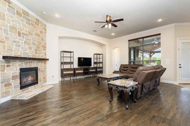 living area with baseboards, ceiling fan, wood finished floors, crown molding, and a fireplace