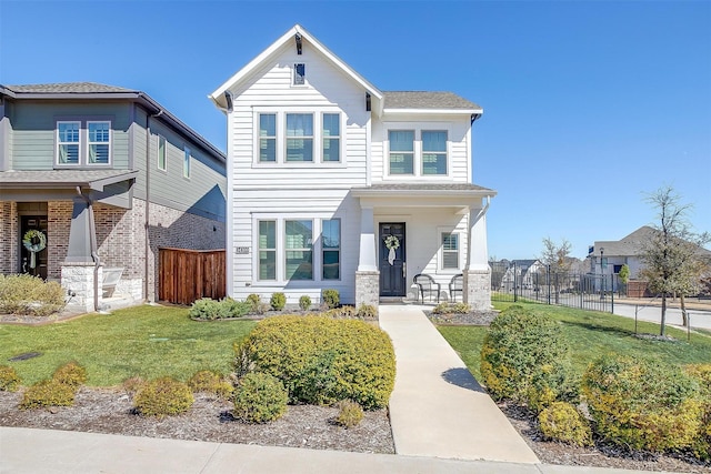 view of front of home featuring covered porch, fence, and a front lawn