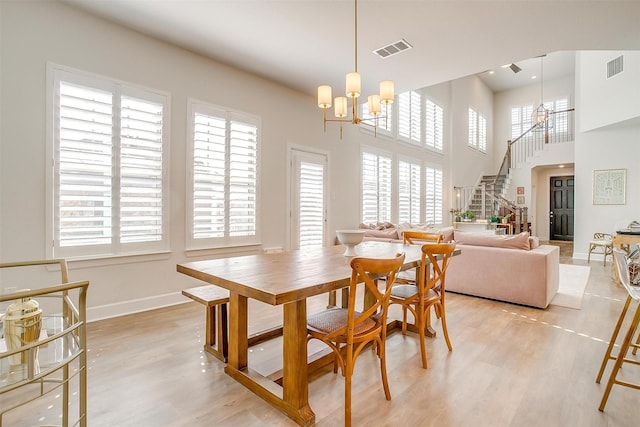 dining space featuring stairs, light wood-style flooring, visible vents, and an inviting chandelier