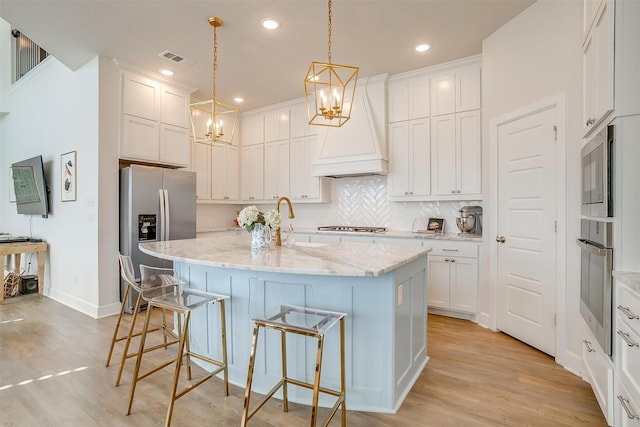 kitchen with a breakfast bar area, stainless steel appliances, visible vents, custom exhaust hood, and decorative backsplash