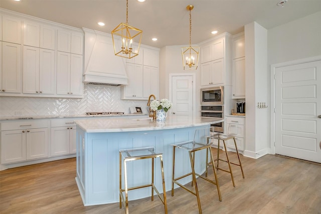 kitchen featuring light wood-style flooring, built in microwave, oven, stovetop, and premium range hood