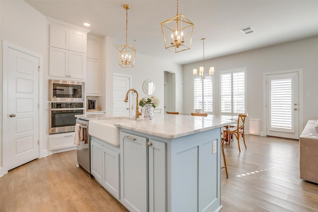 kitchen featuring visible vents, a notable chandelier, stainless steel appliances, light wood-type flooring, and a sink